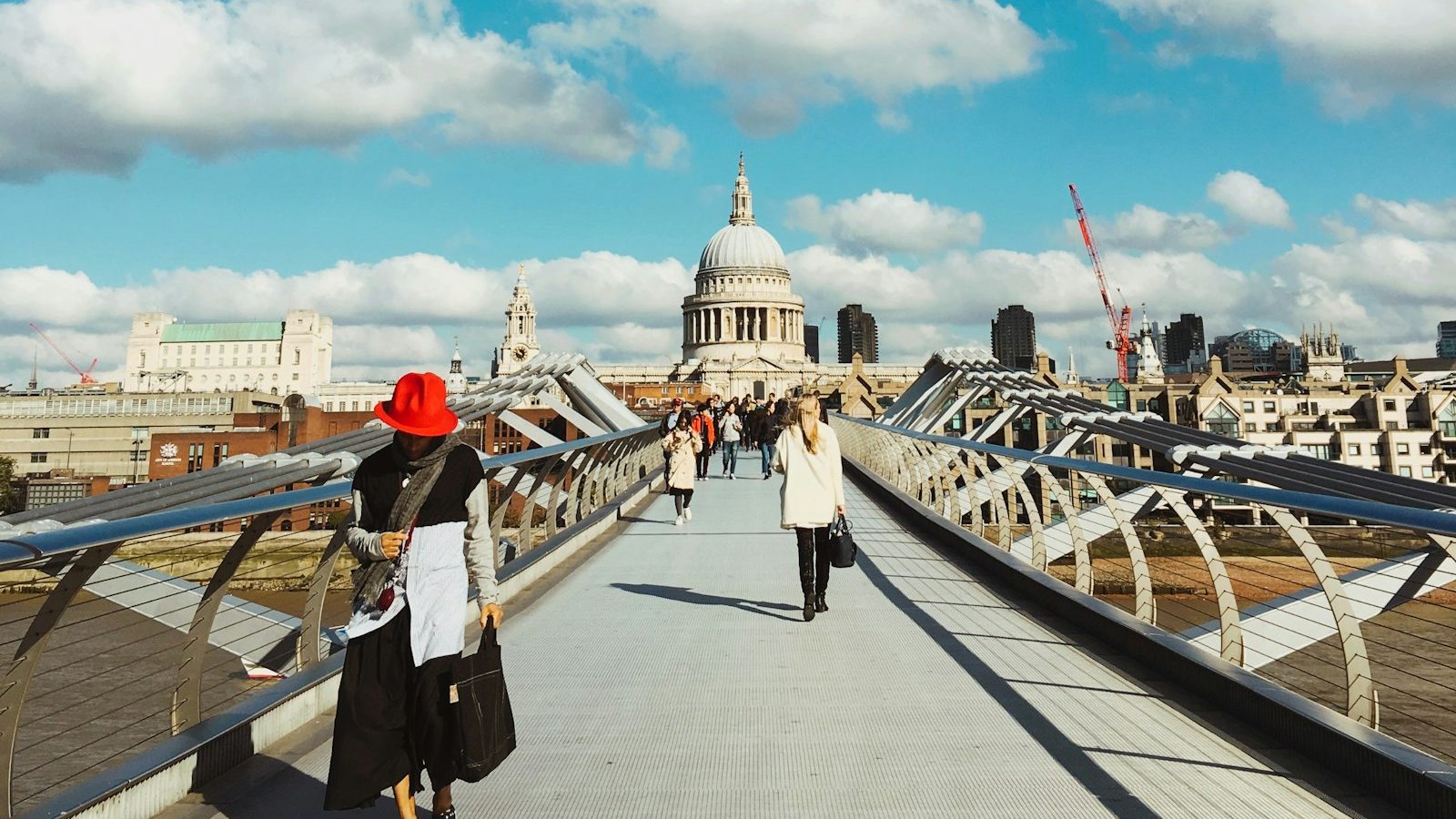 Women walking across the Millennium Bridge in London with St Paul's Cathedral ahead