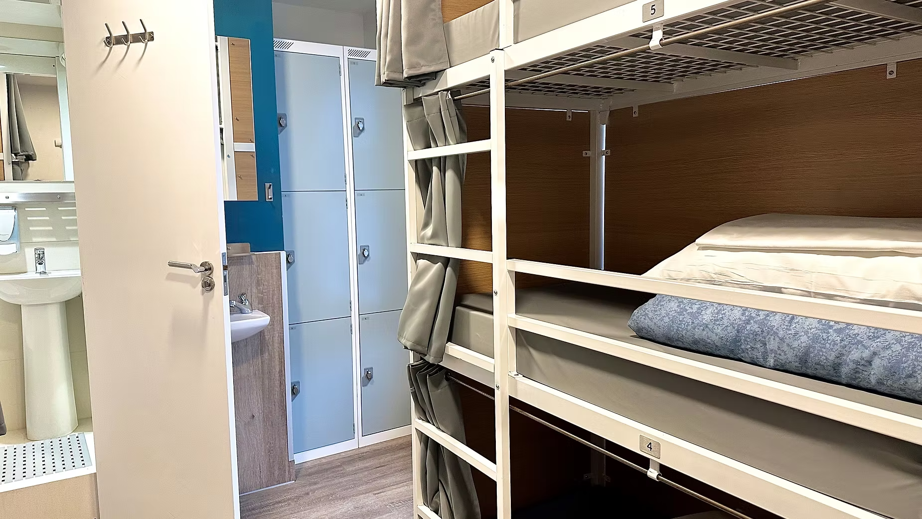 Dorm room with bunk beds, lockers, and en-suite bathroom