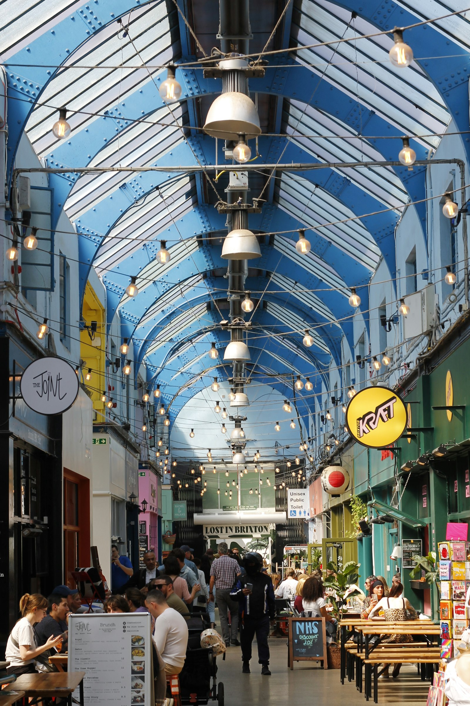 Crowded Camden Market street with colourful stalls and Londoners shopping
